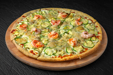 Pizza with zucchini, shrimp and Gorgonzola in a ceramic plate on a dark textured background. Restaurant menu Isolated on black