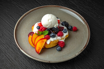 Huge cottage cheese pancake with berries. fruit, ice cream and jam. Hearty tasty breakfast for children in a ceramic plate on a dark textured background. Restaurant menu Isolated on black