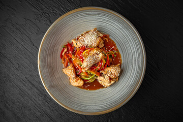 Diet spaghetti of zucchini, carrots and other vegetables with chicken fillet pieces in a ceramic plate on a dark textured background. Restaurant menu Isolated on black