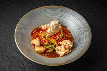Diet spaghetti of zucchini, carrots and other vegetables with chicken fillet pieces in a ceramic plate on a dark textured background. Restaurant menu Isolated on black