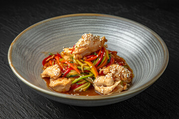 Diet spaghetti of zucchini, carrots and other vegetables with chicken fillet pieces in a ceramic plate on a dark textured background. Restaurant menu Isolated on black