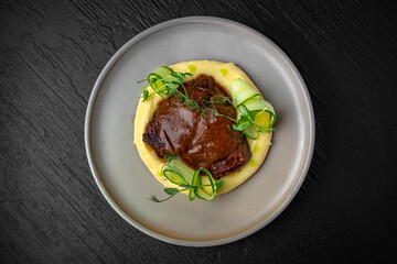 Airy mashed potatoes with liver in sauce in a ceramic plate on a dark textured background. Restaurant menu Isolated on black