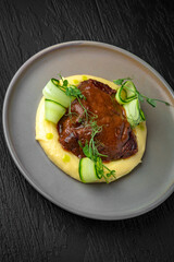 Airy mashed potatoes with liver in sauce in a ceramic plate on a dark textured background. Restaurant menu Isolated on black