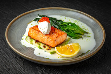 Grilled salmon fillet with zucchini, spinach, cream cheese, garnished with red caviar with cream...