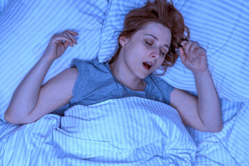 Woman sleeping on her back and snoring in bed at home. Deep sleep. Lady with long brown hair...