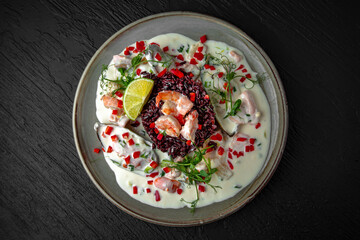 Delicious wild rice risotto, shrimp and creamy seafood broth sauce in a ceramic plate on a dark textured background. Restaurant menu Isolated on black