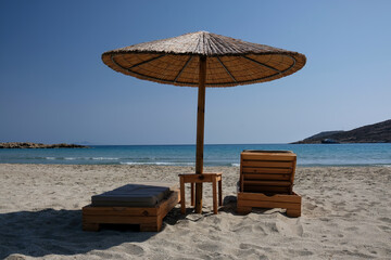Two sunbeds and a sun umbrella at the amazing beach of Manganari  in Ios Greece