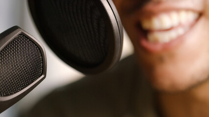 Close up on microphone with blurred podcast or dais host in the background talking