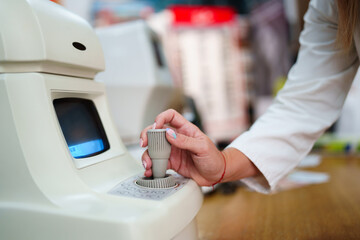 Close up shot of female doctor's hand working on eyesight diopter measuring instrument during...