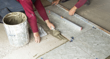 Worker using spatula and putting glue on floor.