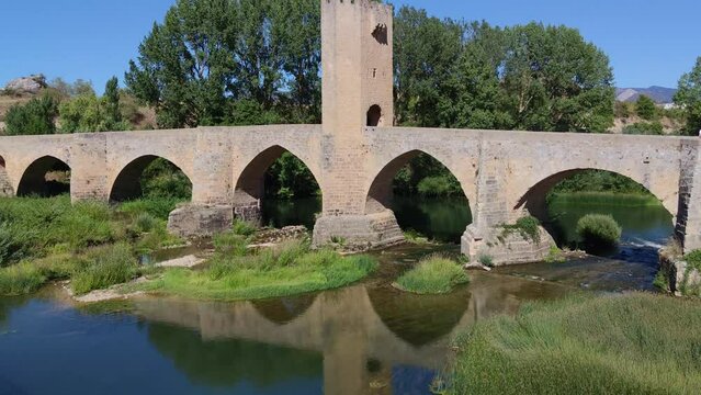Reflejo sobre el río Ebro del puente medieval de origen románico y torre fortificada siglo XIV en Frías, provincia de Burgos, España