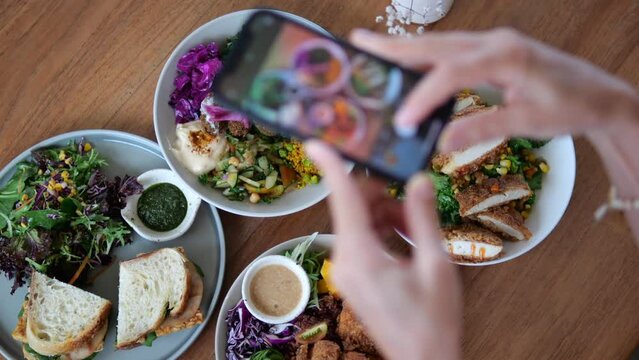 A blogger shoots his food on a smartphone in order to post it on a social network. Photographing beautiful and appetizing food with a high content of vegetables for proper nutrition.