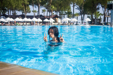 Fototapeta premium Young brunette teen girl posing in a blue swimming pool in a hotel in Turkey