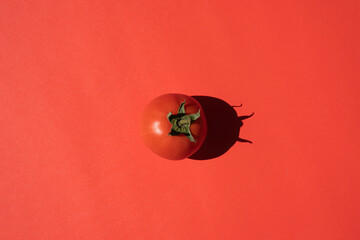 red tomato with a hard shadow on a red background