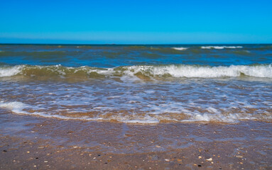 Close-up with waves of sea and sand on beautiful sunny day on beach