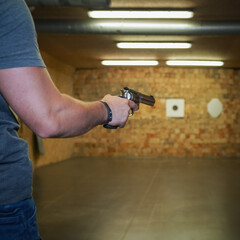 Revolver gun in hand of shooter, shooting range. 