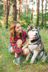 Naklejka na ściany i meble teenage girl playing and having fun with her siberian husky dog. Girl with dog in the forest