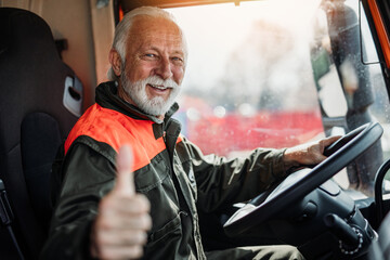 Senior garbage removal worker driving a waste truck. He is showing thumb up. - 524627705