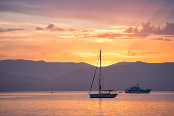 Bright sunset seascape with a sailboat and a ship