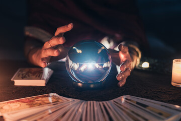 Fortune teller with illuminated crystal ball and tarot cards to prediction future. Hands of astrologists reading future and destiny. Horoscope and forecasting concept. - obrazy, fototapety, plakaty
