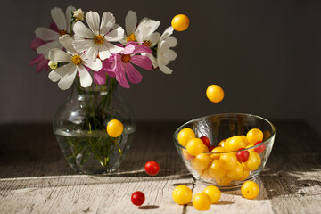 Autumn still life. Still life with a bouquet of flowers and yellow plums. Flowers and fruits on a table. Yellow plums fall into a bowl