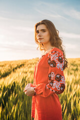 young beautiful woman wearing ukrainian traditional embroidered dress in wheat field during sunset. Stand with Ukraine