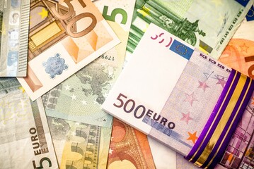 A pack of European currency lies on the background of the Euro
