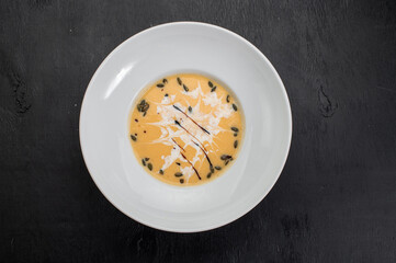 Pumpkin cream soup with seed on wooden background
