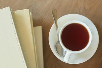 A cup of tea on the table and leather-bound books.