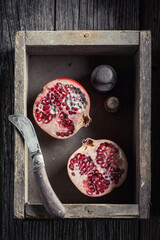 Juicy pomegranate in rustic wooden box with penknife
