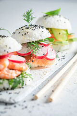 Tasty sushi burger with shrimps and fish on strone plate.