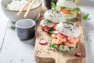 Exquisite sushi burger with avocado and salmon on strone plate.