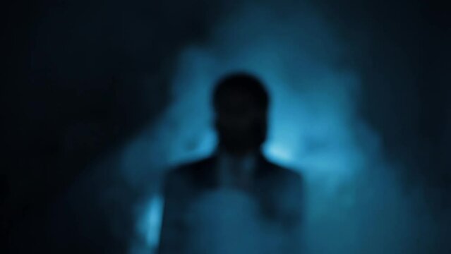 Defocused shot of a man (killer) in the suit with blood on his shirt, smoke, and dramatic light.