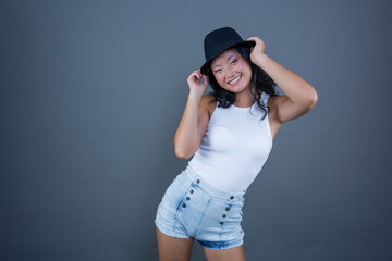 pretty ethnic asian girl posing in tank top, shorts and hat.