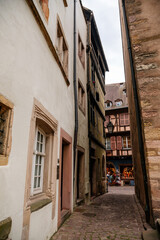 Fototapeta na wymiar Colmar, Alsace, France, 4 July 2022: town capital of Alsatian wine, narrow picturesque street with medieval colorful houses, Timber framing or post-and-beam construction, romantic city at summer day
