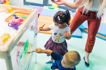 cute little kids painting with brushes in the kindergarten. High quality photo