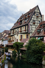 Colmar, Alsace, France, 4 July 2022: town capital of Alsatian wine, narrow picturesque street with medieval colorful houses, Timber framing or post-and-beam construction, Little Venice with channels