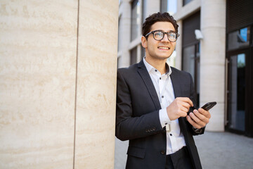 A male manager uses a phone message app, goes to work in a new office in a suit