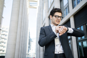 The manager, a man with glasses, watches a smartwatch, uses an app, goes to work in a new office in a suit