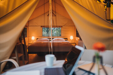 Interior of Cozy open glamping tent with light inside during dusk. Luxury camping tent for outdoor...
