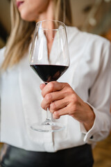 close up on midsection of unknown woman hold glass of red wine