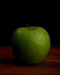 Granny Smith green apple on black with fine water droplets