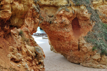 Close Up of Small Cave in Rocky Cliff on Sandy Beach 