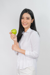 Portrait photo of a young beautiful asian female lady smile happily and warm wearing a white shirt holding a green apple