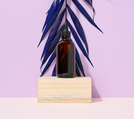 A brown glass bottle with a pipette on purple background. Containers for cosmetics, oils, serums