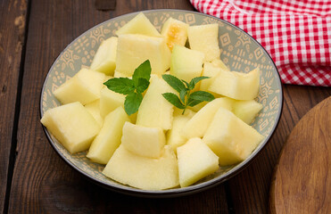 Sliced pieces of melon in a round gray plate on the table