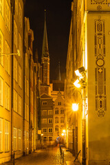 Night illumination on an old medieval street in the historical center of Gdansk, ghosts of human figures on a narrow street, Poland tourist attractions