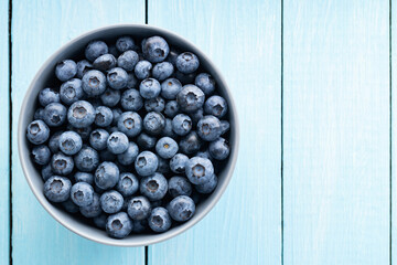 Blueberries in a bowl. Fresh blueberries on blue boards. Top view. Copy space