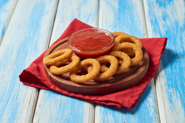 Homemade crunchy fried onion rings with tomato sauce