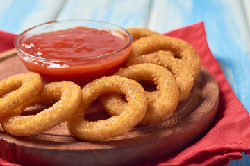 Plate of crunchy onion rings with ketchup sauce
